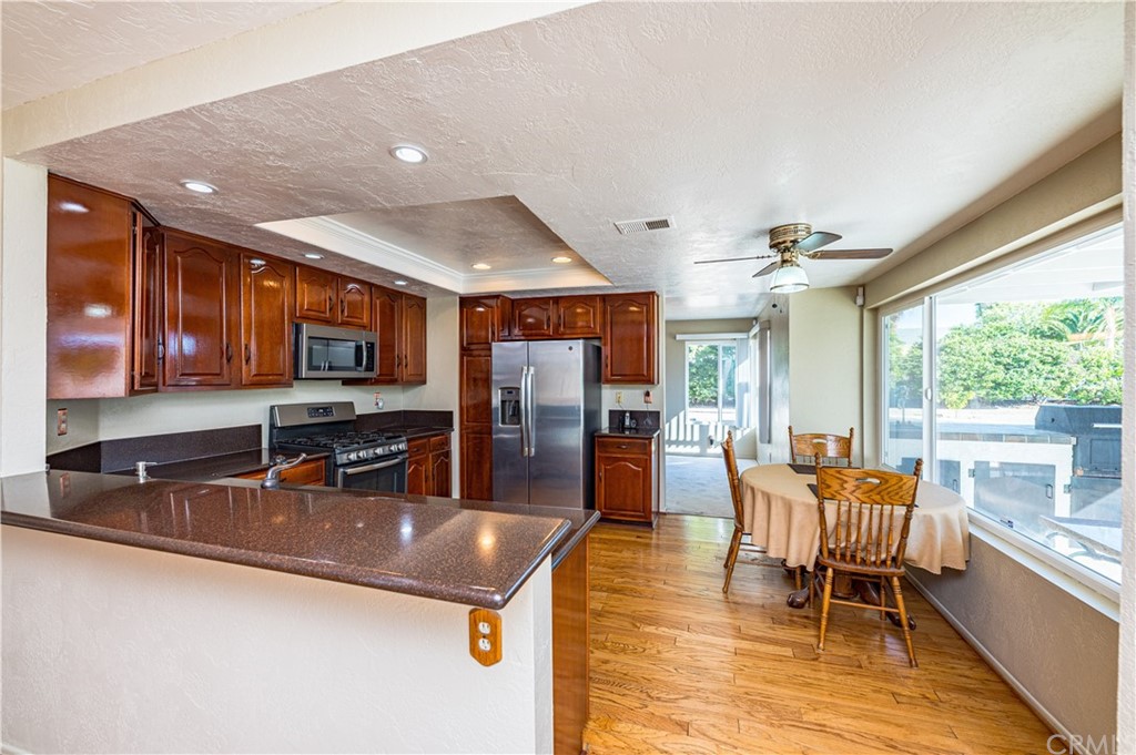 22041 Windtree Avenue Wildomar, CA 92595 - Photo 13 of 47 a kitchen with stainless steel appliances granite countertop a sink a stove top oven a dining table and chairs with the view of kitchen