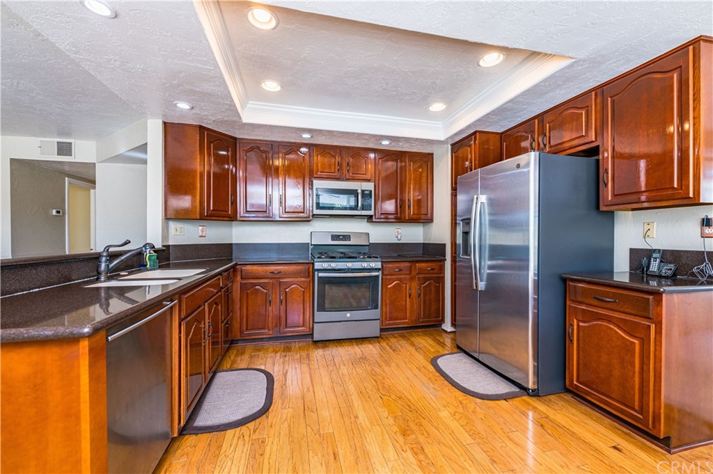 22041 Windtree Avenue Wildomar, CA 92595 - Photo 14 of 47 a kitchen with stainless steel appliances granite countertop a refrigerator a sink dishwasher a stove with wooden cabinets and floor
