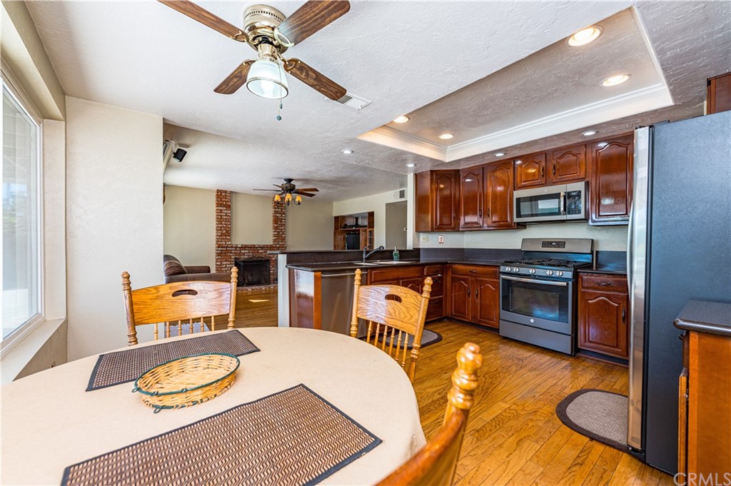 22041 Windtree Avenue Wildomar, CA 92595 - Photo 15 of 47 a kitchen with stainless steel appliances granite countertop a stove top oven a sink a dining table and chairs with wooden floor