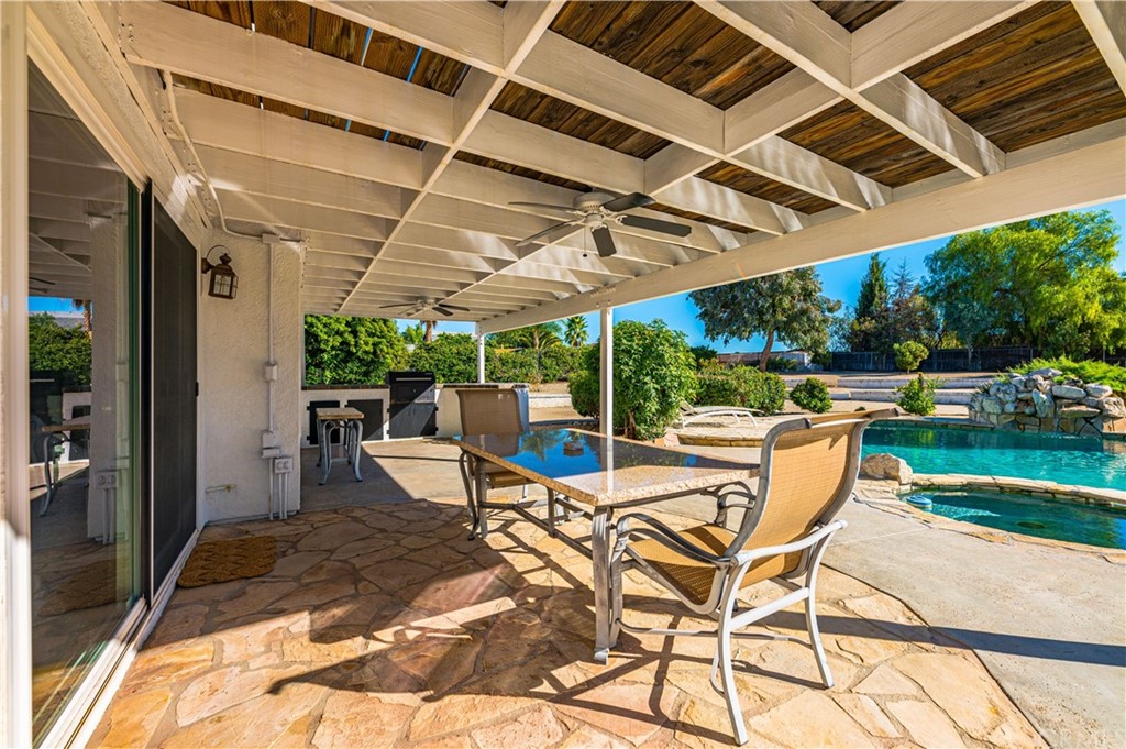 22041 Windtree Avenue Wildomar, CA 92595 - Photo 32 of 47 a view of a patio with a table and chairs under an umbrella next to a yard
