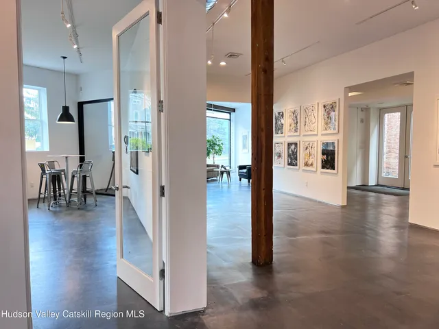 a view of a hallway with wooden floor windows and a living room