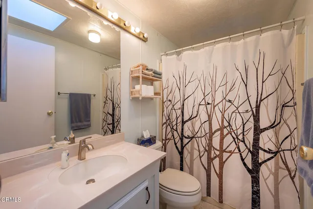 a bathroom with a granite countertop sink toilet a large mirror a bathtub and window