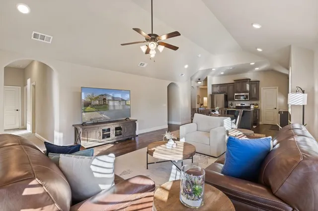 a living room with furniture kitchen view and a chandelier