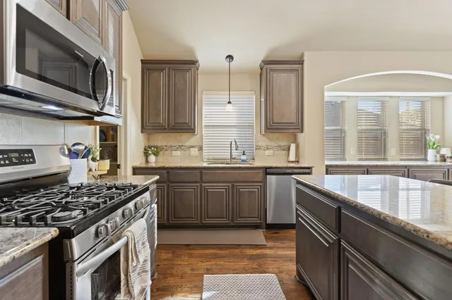 a kitchen with stainless steel appliances granite countertop a stove sink and cabinets