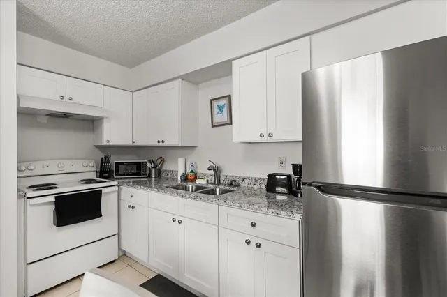 a kitchen with granite countertop white cabinets and white appliances