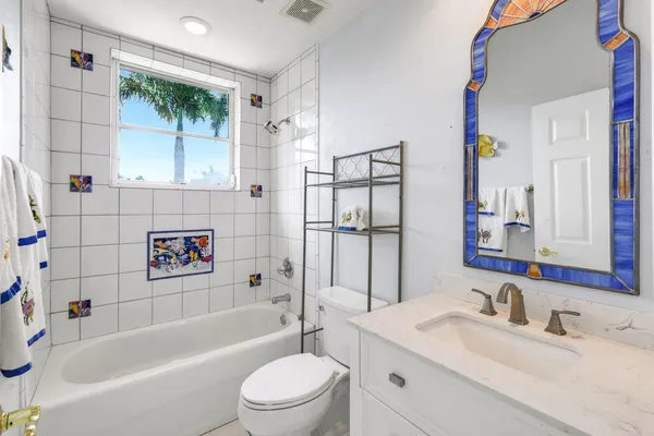 a bathroom with a sink a toilet a mirror a vanity and bathtub