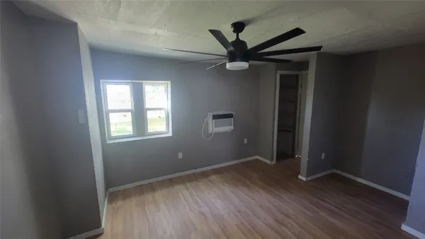 an empty room with wooden floor closet and windows