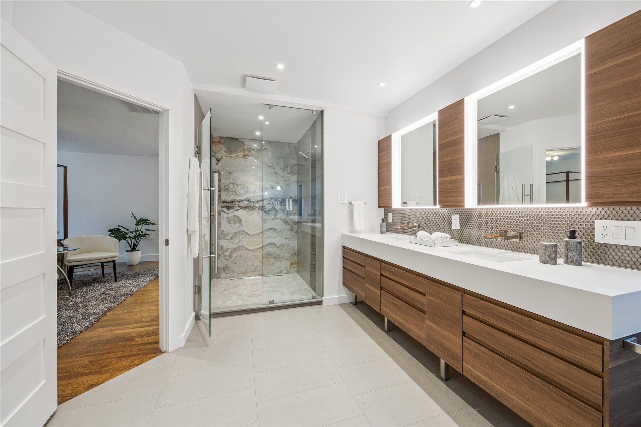 2420 Locke Lane Houston, TX 77019 - Photo 20 of 37 The Primary En-suite Boutique-style Bathroom is sleek and serene, and features wood-look European cabinetry, double sinks with built-in LED mirrors, an oversized shower with beautiful stone surround, soaking tub, additional linen storage, and walk-in closet.