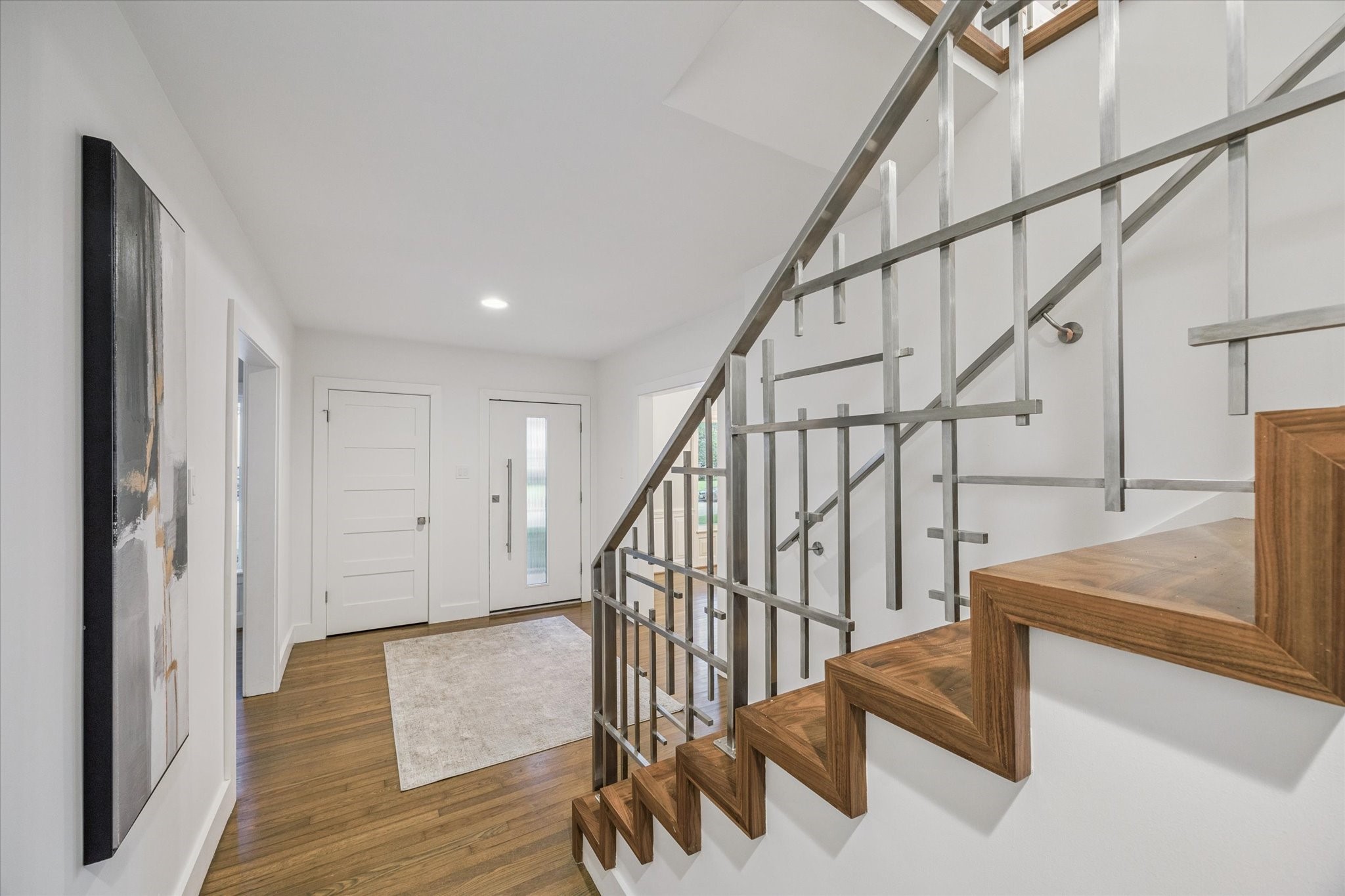 2420 Locke Lane Houston, TX 77019 - Photo 3 of 37 The Entry features a modern, single-light door with fluted glass for extra privacy, original hardwood floors, coat closet and wood-treaded staircase with decorative metal railing.
