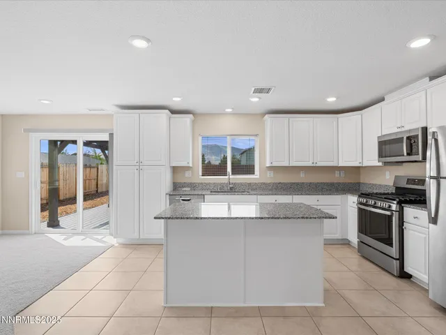 a kitchen with kitchen island granite countertop a stove sink and cabinets