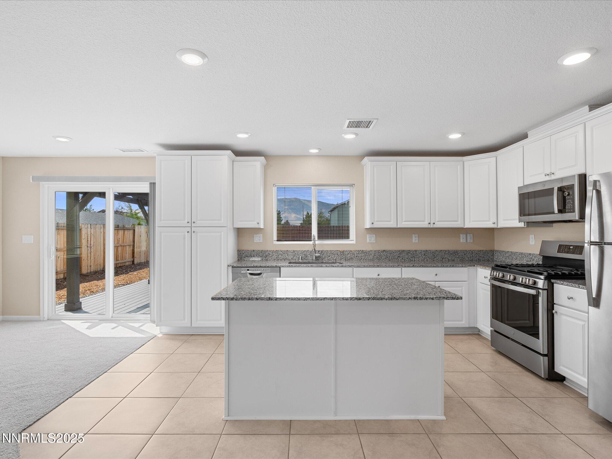 8933 Quail Falls Drive Reno, NV 89506 - Photo 2 of 22 a kitchen with kitchen island granite countertop a stove sink and cabinets