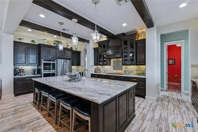 a kitchen with granite countertop center island wooden floor stainless steel appliances and cabinets