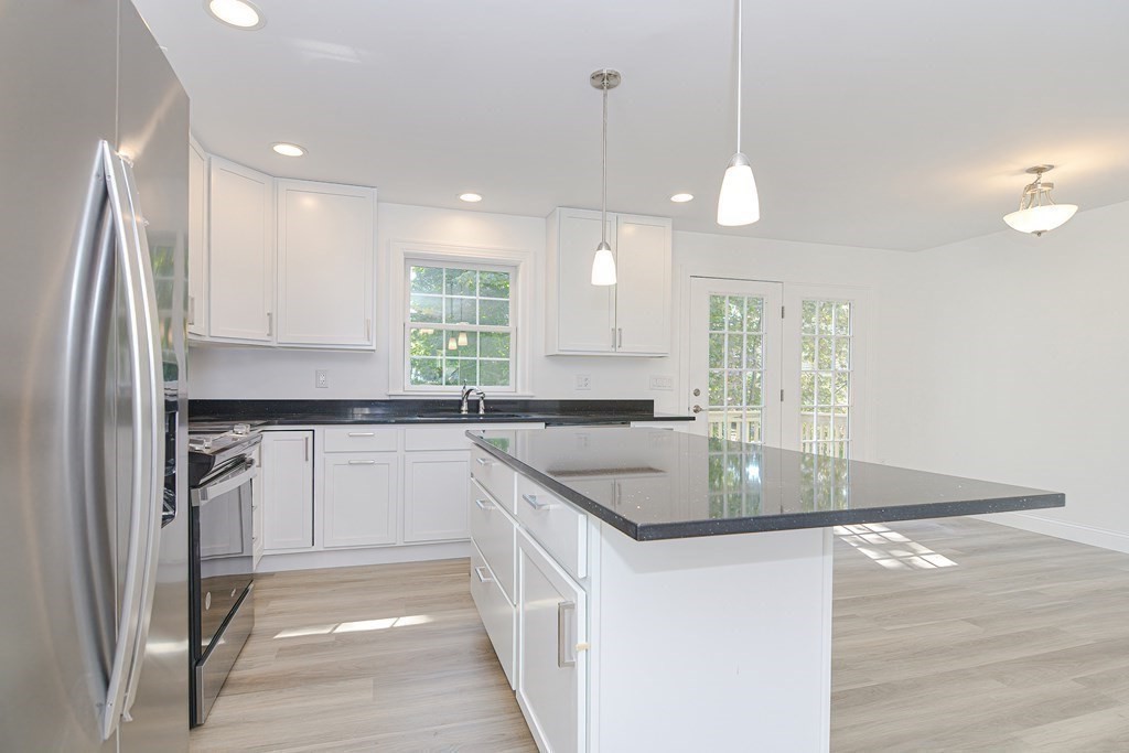 a kitchen with stainless steel appliances granite countertop a sink a stove a refrigerator and island with wooden floor