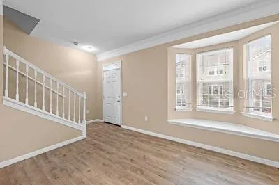 a view of an empty room with wooden floor and a window