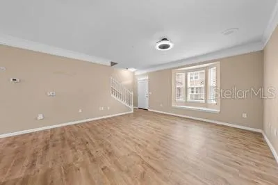 a view of empty room with wooden floor and windows