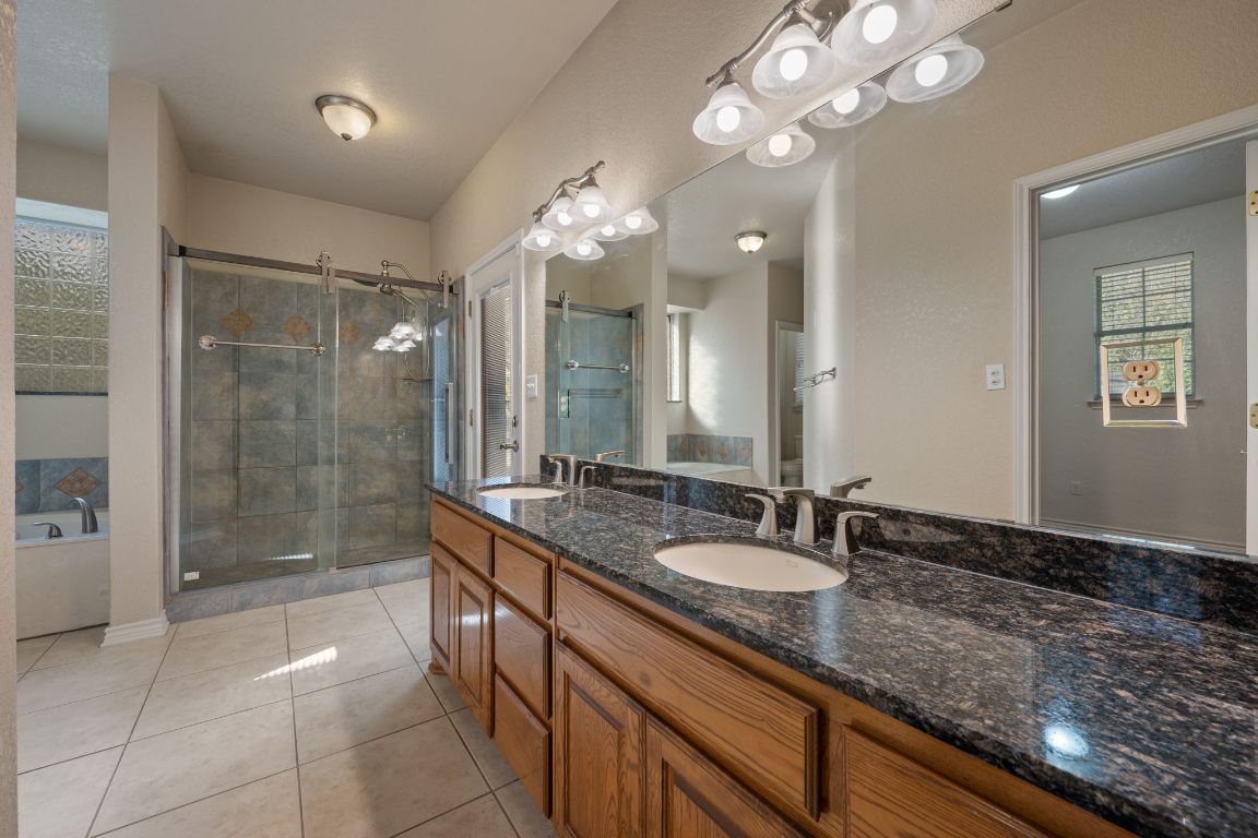 686 Benchmark Trail Belton, TX 76513 - Photo 14 of 38 a bathroom with a granite countertop sink a large mirror and a shower