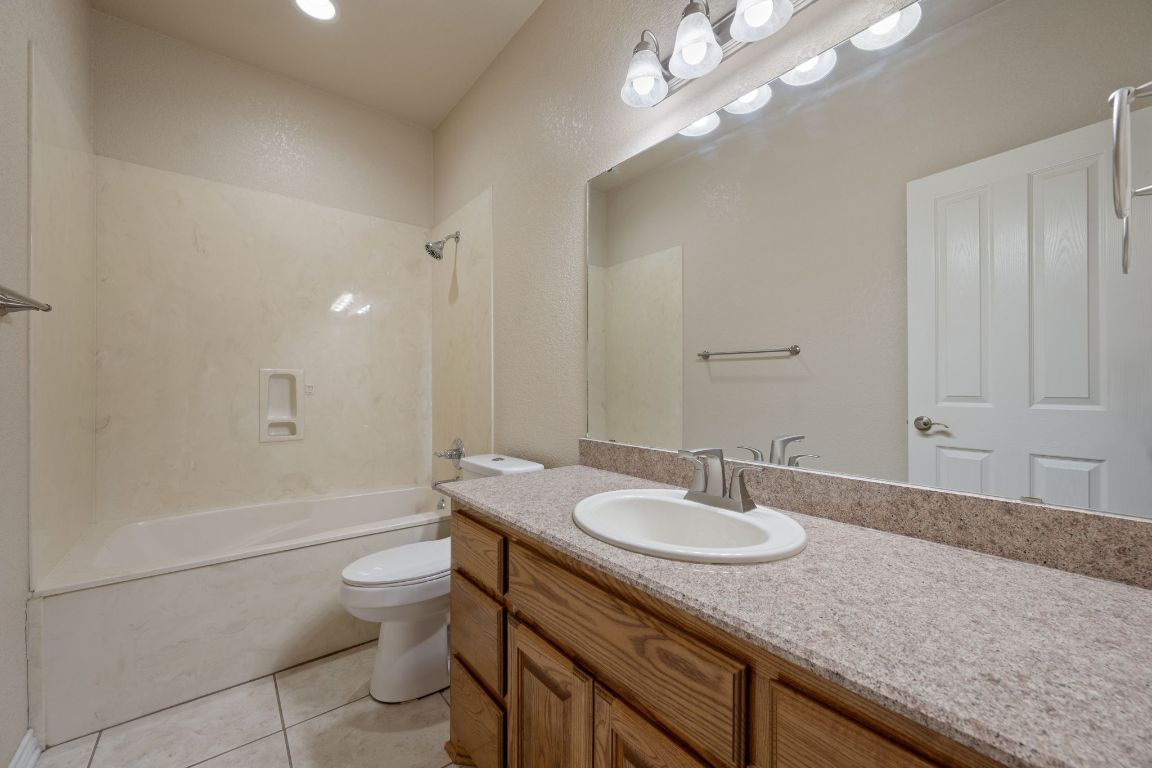 686 Benchmark Trail Belton, TX 76513 - Photo 18 of 38 a bathroom with a granite countertop sink a toilet a mirror and shower