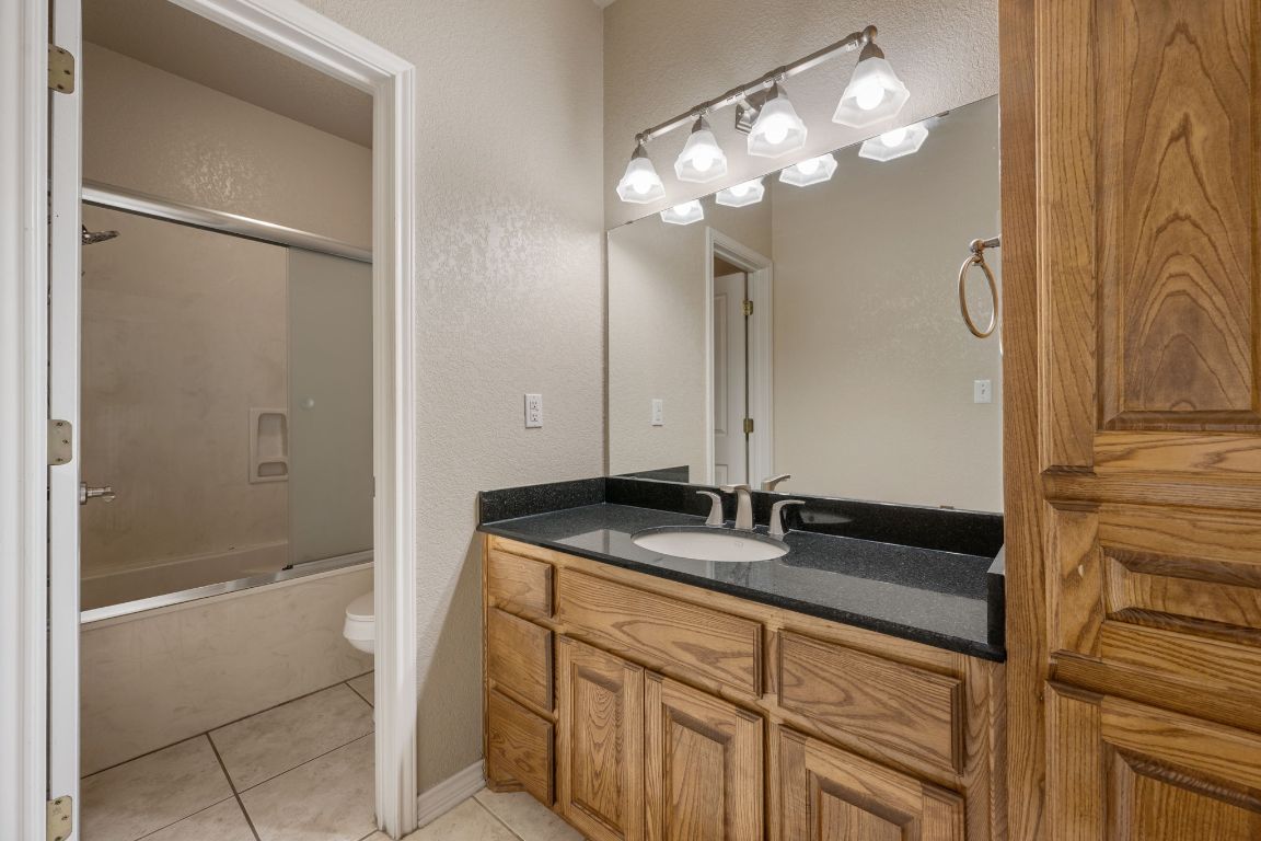 686 Benchmark Trail Belton, TX 76513 - Photo 22 of 38 a bathroom with a granite countertop sink a mirror and shower