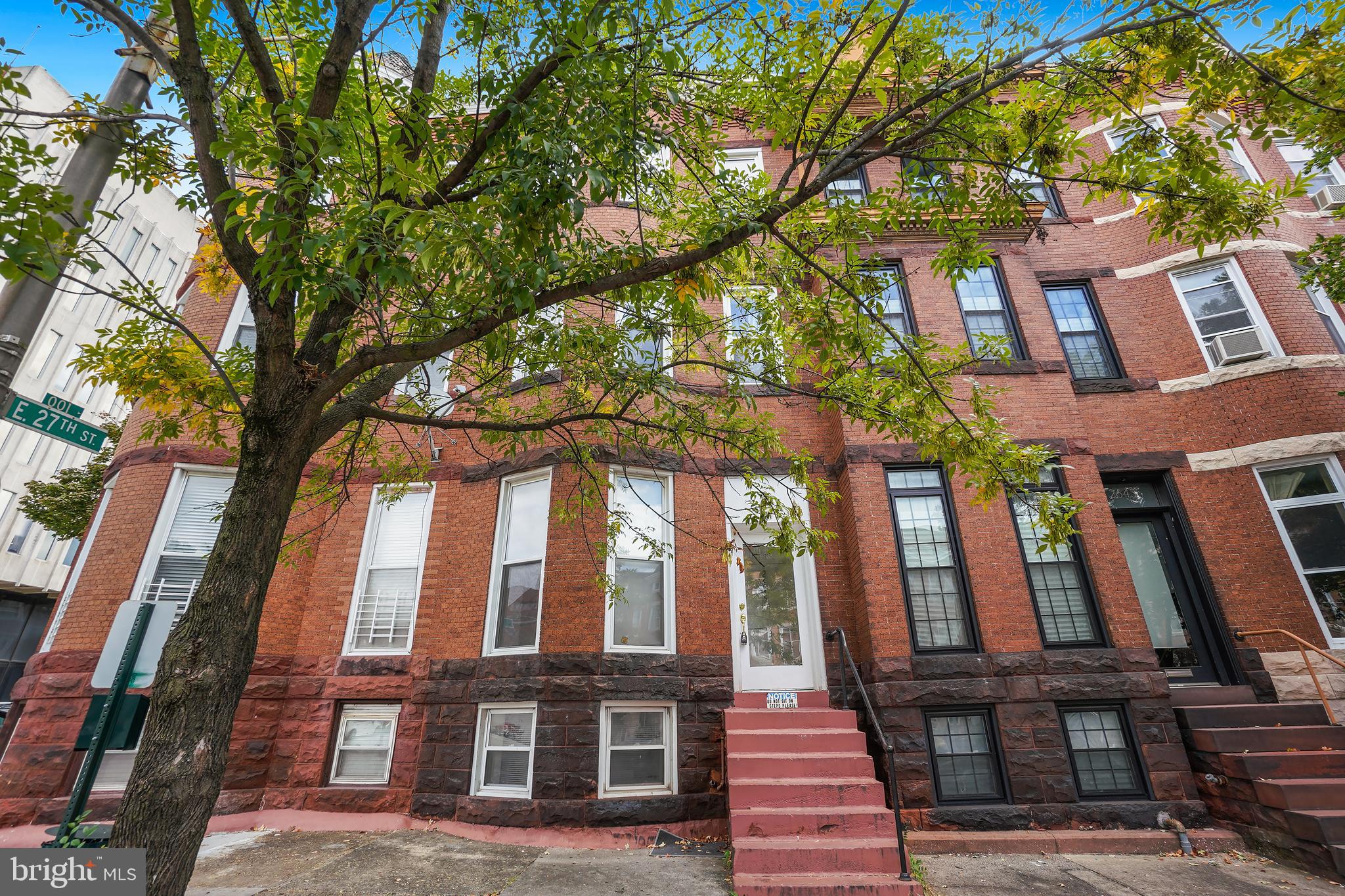 a view of a brick building next to a large tree