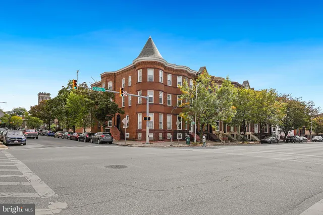 a front view of a building with lot of cars and trees