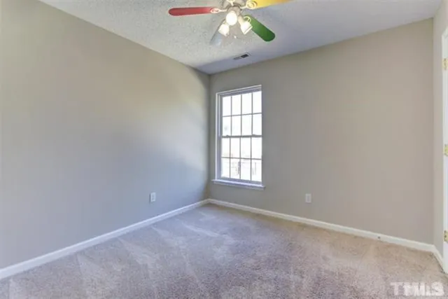 an empty room with a chandelier fan and windows
