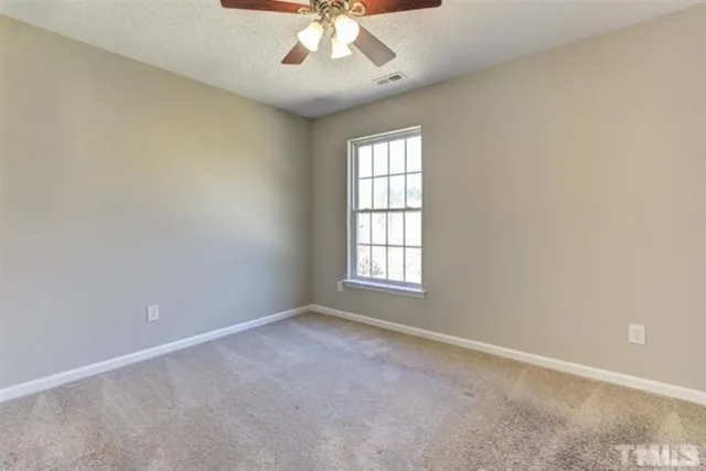 an empty room with a chandelier fan and windows
