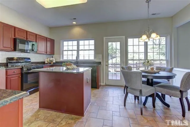 a kitchen with stainless steel appliances granite countertop a stove a sink a dining table and chairs