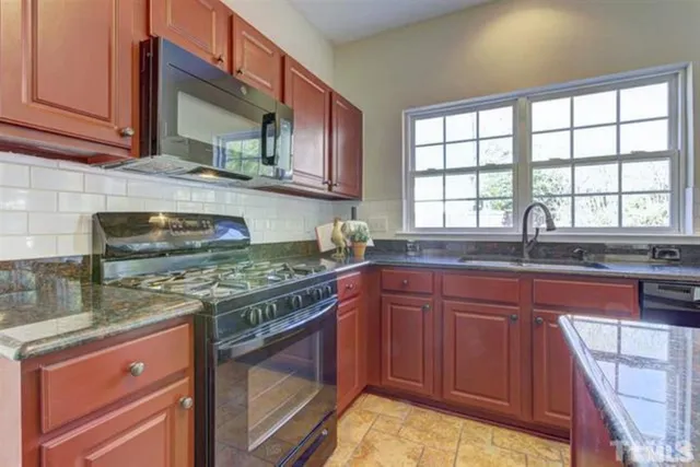 a kitchen with stainless steel appliances granite countertop a stove sink and cabinets