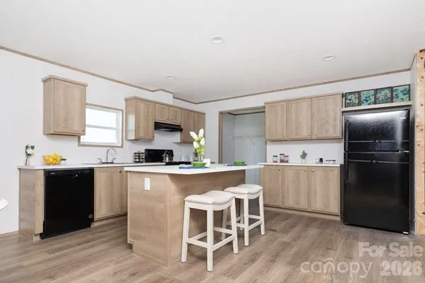 a kitchen with stainless steel appliances granite countertop a refrigerator a stove a sink a dining table and chairs with wooden floor