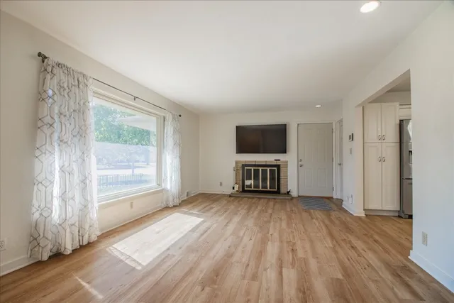 a view of an empty room with a window and wooden floor