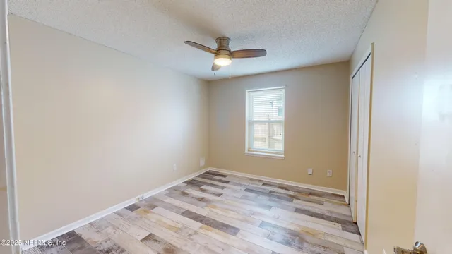an empty room with a window and ceiling fan