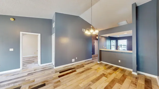 a view of an empty room with wooden floor and a bedroom