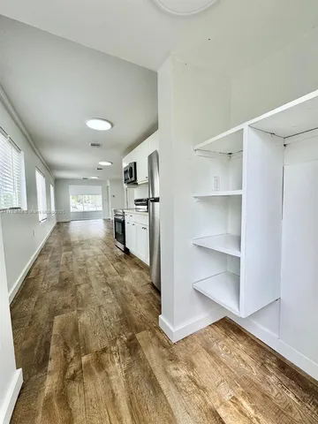 a view of empty room with cabinet and wooden floor