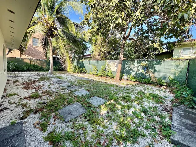 a view of a yard with plants and trees