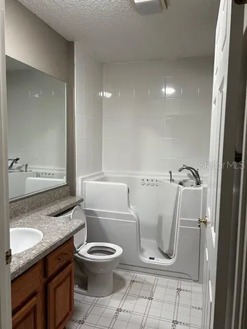 a bathroom with a granite countertop toilet a sink and a mirror