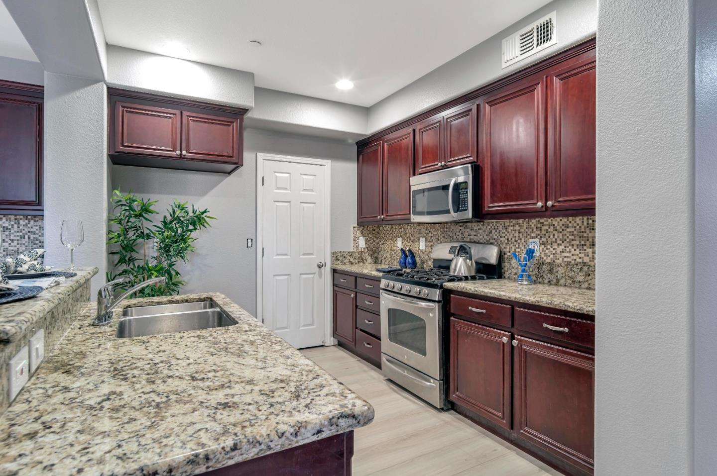 1814 Snell Place Milpitas, CA 95035 - Photo 11 of 49 a kitchen with kitchen island granite countertop wooden cabinets and a stove top oven