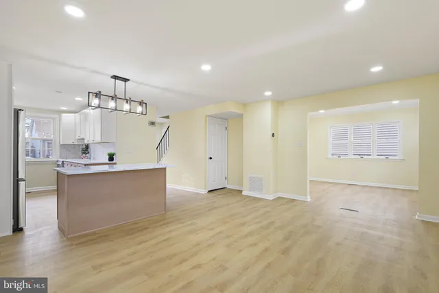 a view of kitchen and empty room with wooden floor