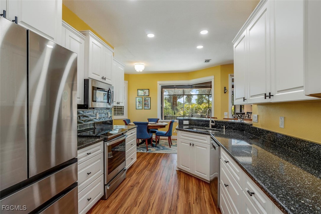 139 Crevalle Road Rotonda West, FL 33947 - Photo 8 of 24 a kitchen with stainless steel appliances granite countertop a stove top oven a sink dishwasher a refrigerator and white cabinets with wooden floor