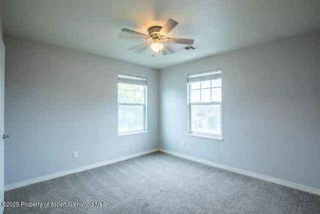 an empty room with window and ceiling fan