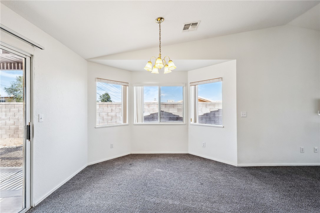 2524 South Ridge Avenue Bullhead City, AZ 86429 - Photo 17 of 64 Spare room featuring vaulted ceiling, a chandelier, dark carpet, and baseboards