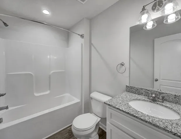 a bathroom with a granite countertop sink a toilet and shower
