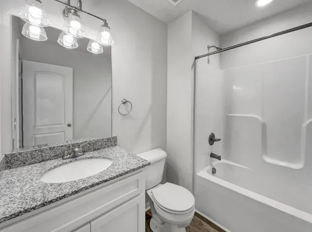 a bathroom with a granite countertop sink a toilet and shower