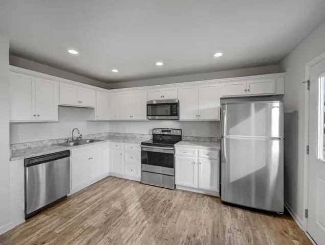 a kitchen with granite countertop stainless steel appliances and wooden floor