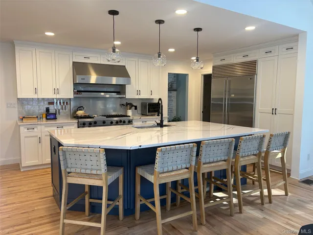 a kitchen with granite countertop a dining table chairs and wooden floor