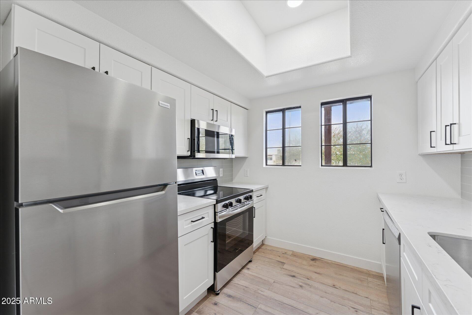 3434 East Baseline Road, Unit 265 Phoenix, AZ 85042 - Photo 10 of 19 a kitchen with a refrigerator stove and white cabinets