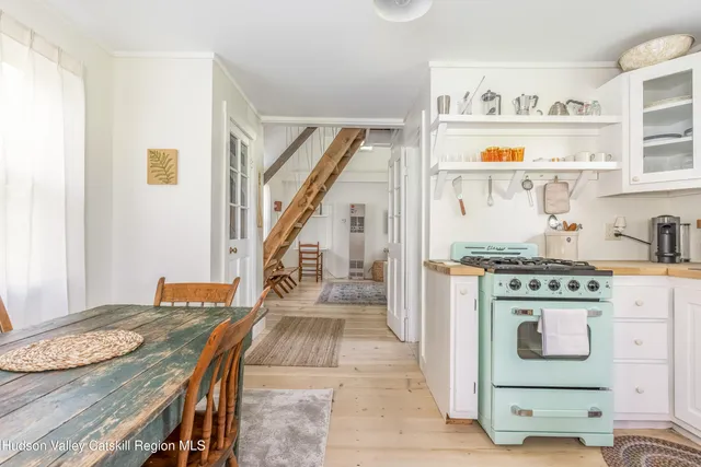 a kitchen with kitchen island stainless steel appliances stove a dining table and chairs with wooden floor