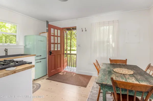 a kitchen with stainless steel appliances granite countertop a stove a refrigerator a sink a dining table and chairs with wooden floor