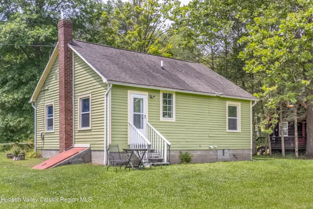 a view of a house with a yard chairs and a small yard
