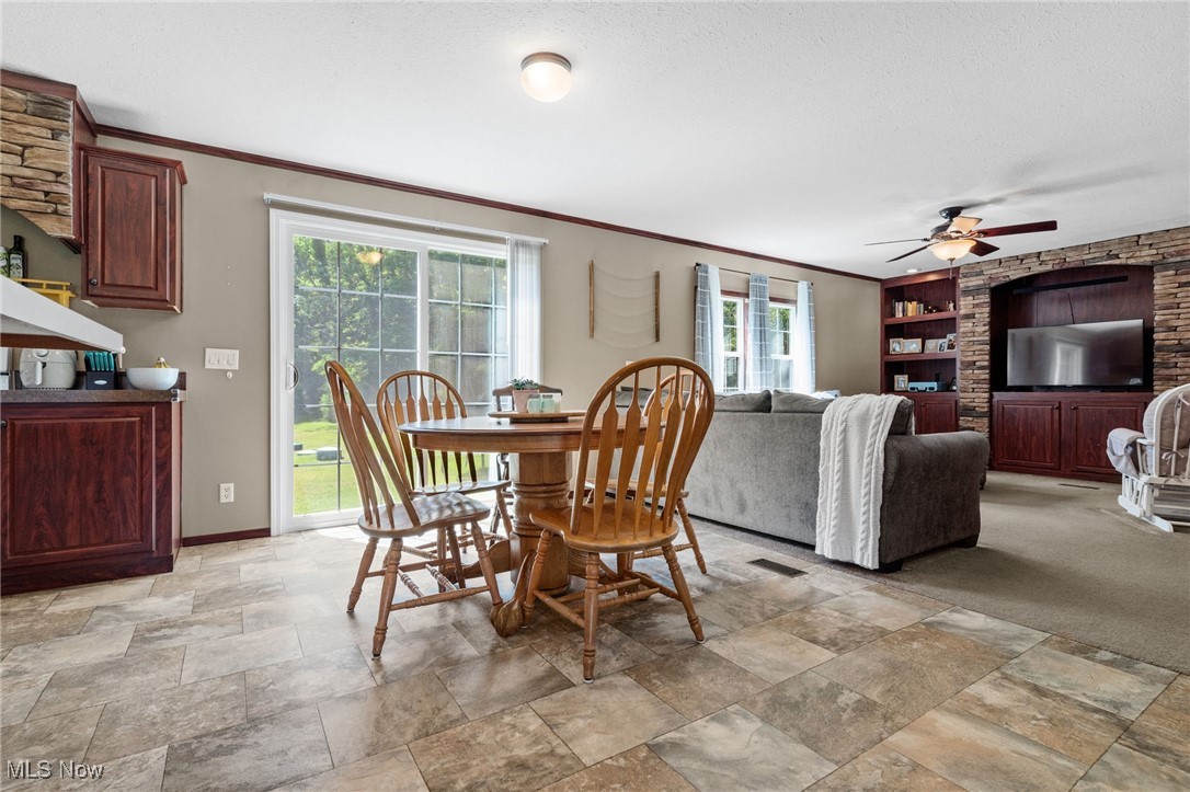 1467 Notman Road Deerfield, OH 44411 - Photo 8 of 37 Dining area featuring ornamental molding, ceiling fan, light stone finish floors, a textured ceiling, and built in shelves
