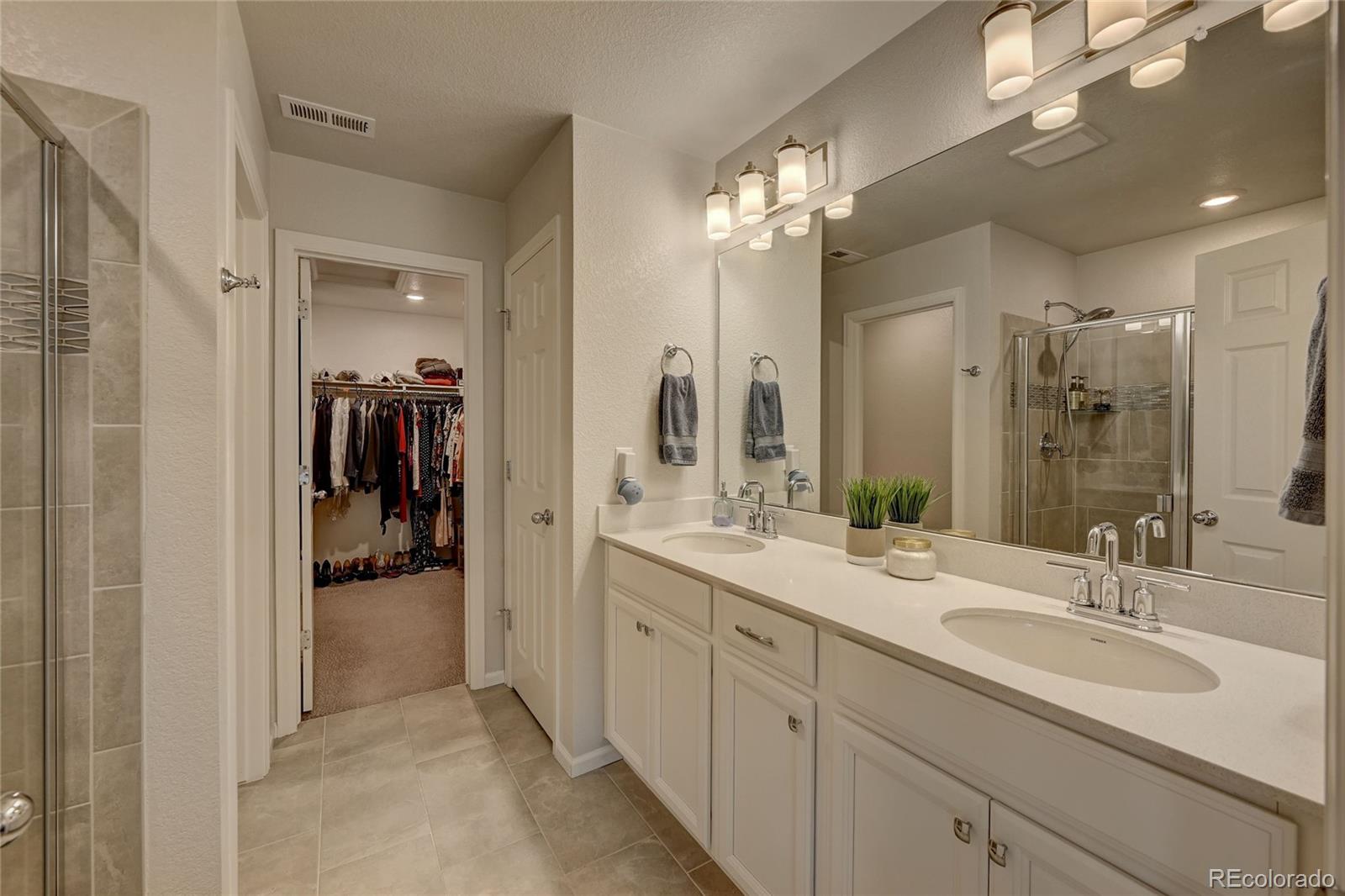 7203 Bedlam Drive Castle Pines, CO 80108 - Photo 20 of 39 a en suite bathroom with a double vanity sink a mirror and shower